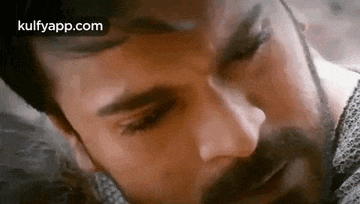 a close up of a man 's face with a beard and a beard .