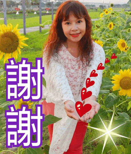 a woman in front of a field of sunflowers holds a heart in her hands