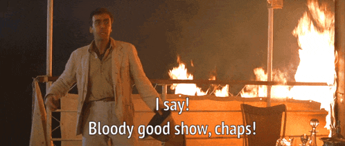 a man in a suit stands in front of a fire and says bloody good show chaps