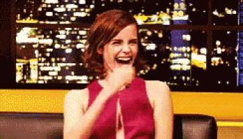 a woman in a red dress is laughing while sitting on a couch at night .