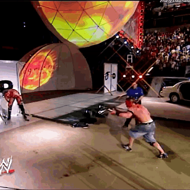 two wrestlers are fighting on a stage with a wwe logo on the ground