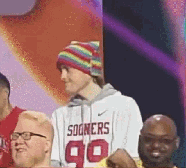 a man wearing a rainbow hat and a sooners jersey