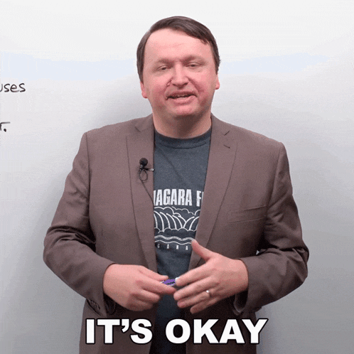 a man in a suit says it 's okay in front of a white board