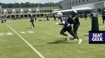 a group of football players are running on a field with a sign that says seat geek .