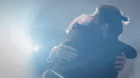 a man and a woman are hugging each other in a dark room .
