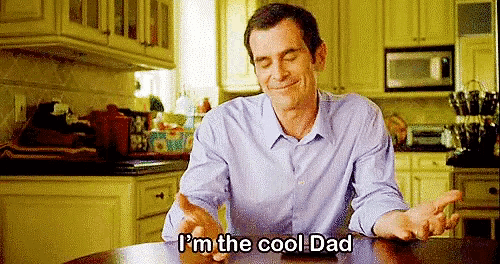 a man is sitting at a table in a kitchen with his eyes closed and says `` i 'm the cool dad '' .