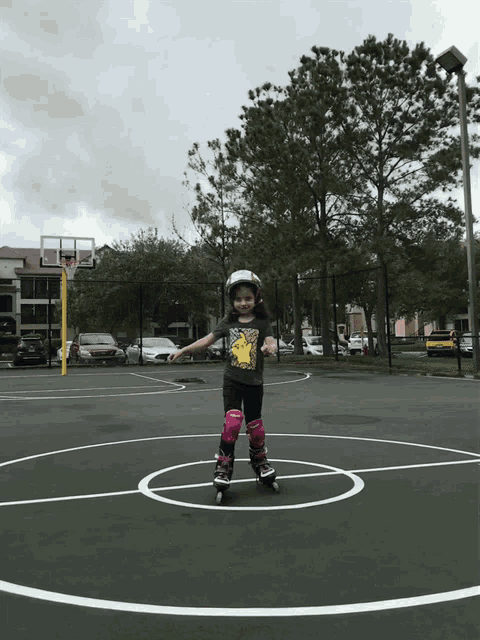 a little girl rollerblading on a basketball court