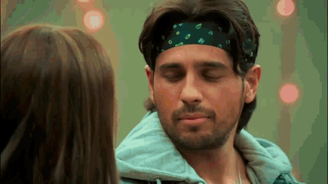 a man with a bandana on his head is looking at a woman .