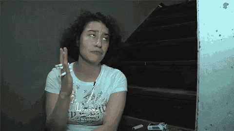 a woman is smoking a cigarette and wearing a shirt that says disney on it