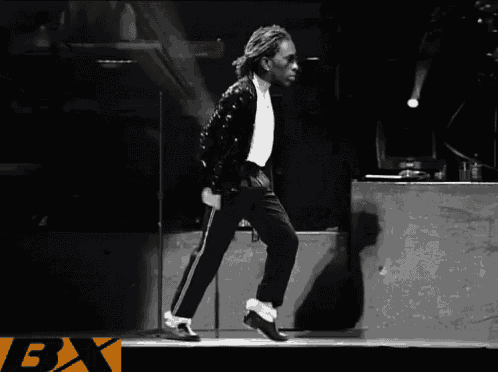 a black and white photo of a man walking on a stage with the letter bx in the corner