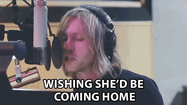 a man singing into a microphone with the words wishing she 'd be coming home written below him