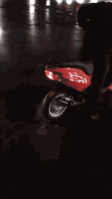 a person riding a motorcycle in a dark parking lot