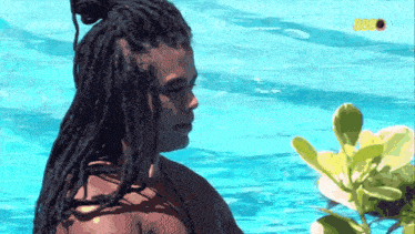 a man with dreadlocks is standing in a swimming pool with a sign that says 2020