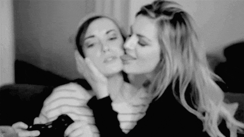 a black and white photo of two women kissing each other .