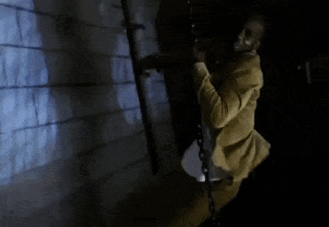 a man is chained to a wall in a dark room while wearing a white shirt .