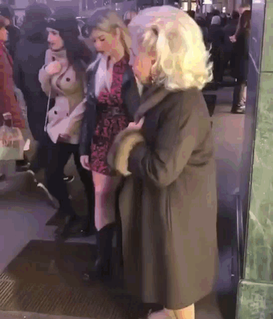 a woman in a fur coat is standing next to another woman in a dress .