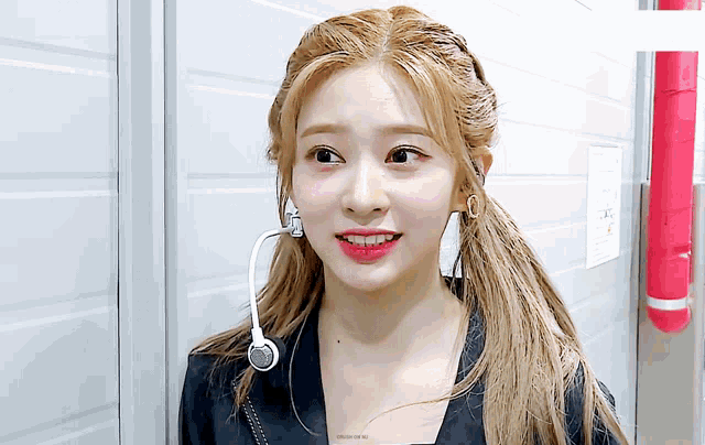 a woman wearing a ponytail and a microphone with the word design on the bottom right