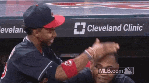 two baseball players are giving each other a high five in front of a cleveland clinic advertisement