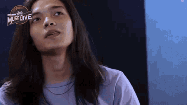a woman with long hair is wearing a purple shirt and looking up at the sky .