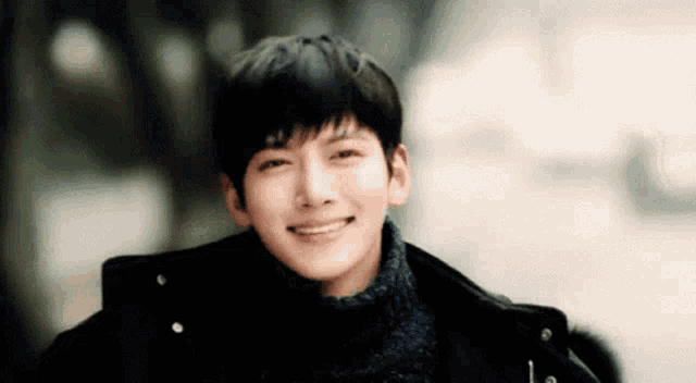 a young man wearing a sweater and a jacket is smiling .