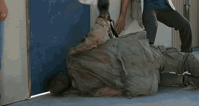 a man laying on the ground holding a gun while another man stands behind him