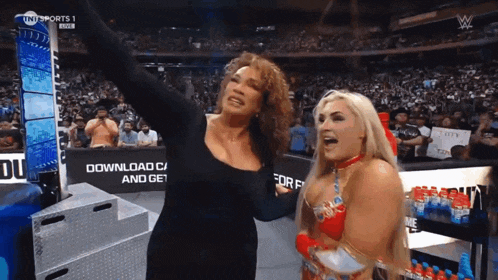 two women are standing next to each other in a stadium with a sign that says download c and get