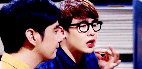 a man wearing glasses talks to another man in a blue shirt