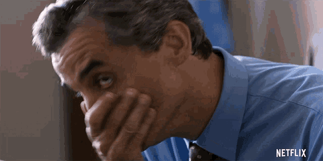 a man in a blue shirt and tie with a netflix logo on the bottom right