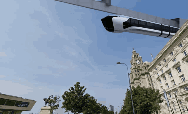 a clock tower with a statue in front of it and a train flying over it