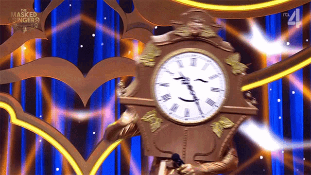 a clock on a stage with a masked singer logo in the background
