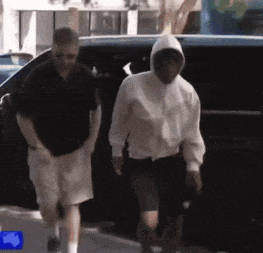 a man wearing a white hoodie is walking with another man
