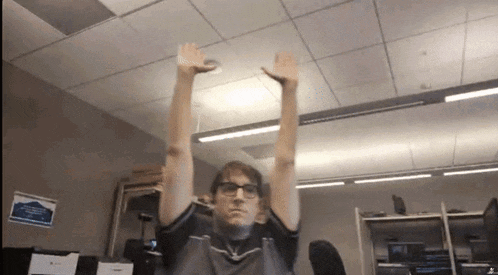 a man with glasses is stretching his arms in a room .