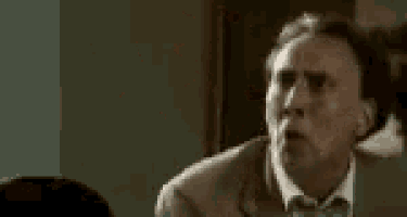 a man in a suit and tie is standing in a dark room .