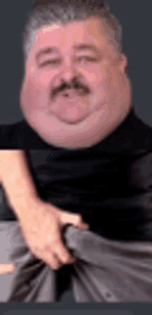 a man with a big face and a mustache is holding his pants .