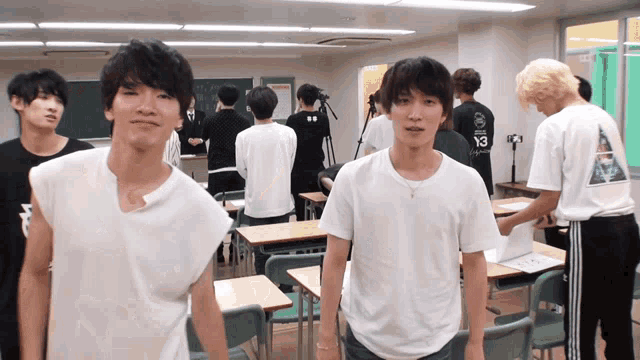 a group of young men are standing in a classroom wearing white shirts with the number 13 on the back