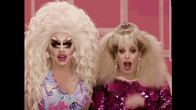 two drag queens are standing next to each other with their mouths wide open