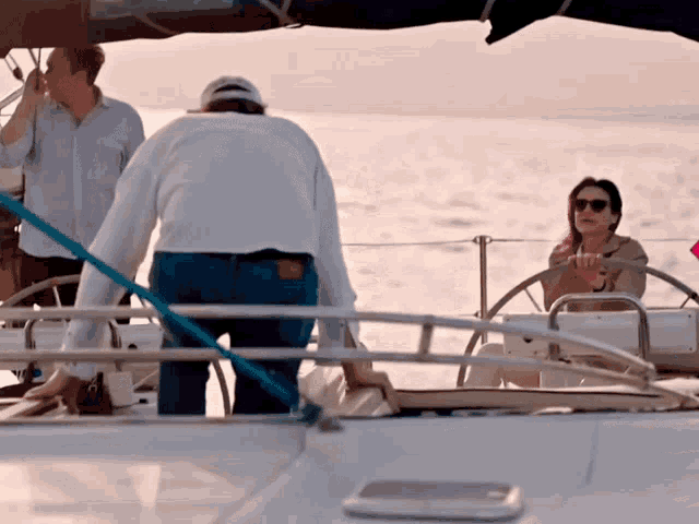 a woman sits at the helm of a boat while a man stands behind her
