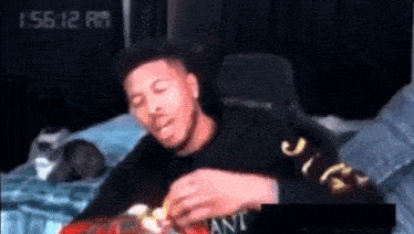 a man is eating a bag of chips while sitting in a chair .