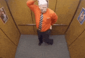 a man in a red shirt and tie is standing in an elevator with a woman .