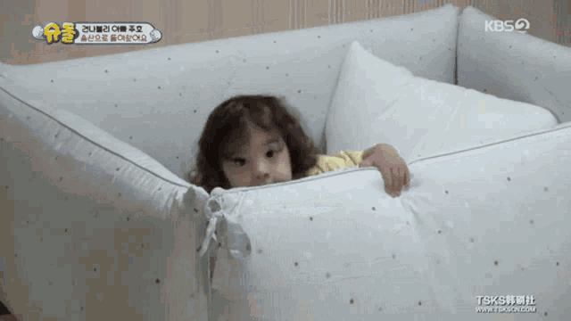 a baby is laying in a crib with a kbs logo on the bottom