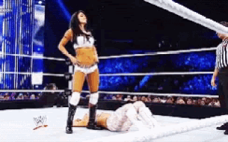a woman is standing in a wrestling ring with a referee watching