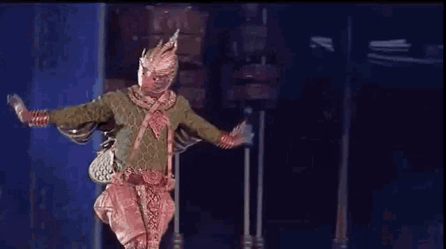 a man in a costume is dancing on a stage in front of a blue background .