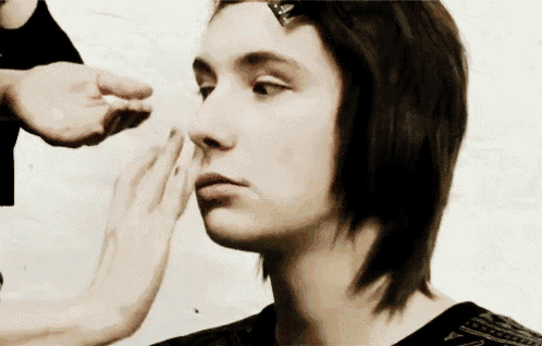 a woman is getting her makeup done by a person .