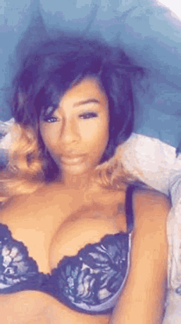 a woman in a bra is laying on a bed .
