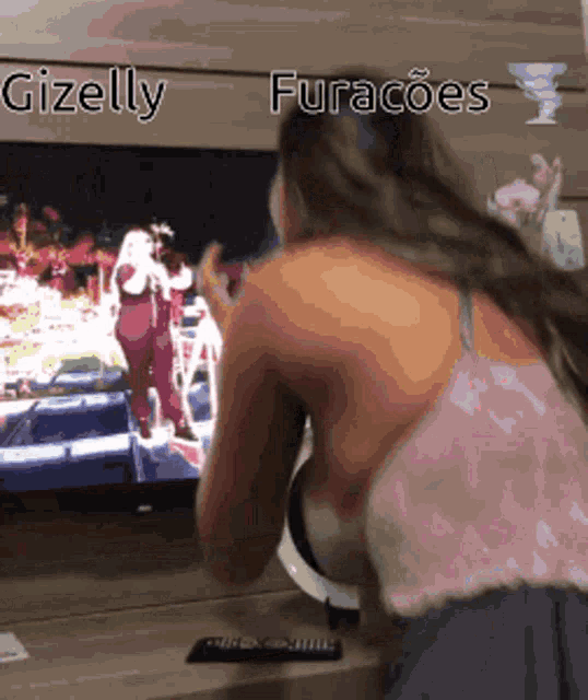 a woman is looking at a tv screen with the words gizelly furacaoes written on the bottom