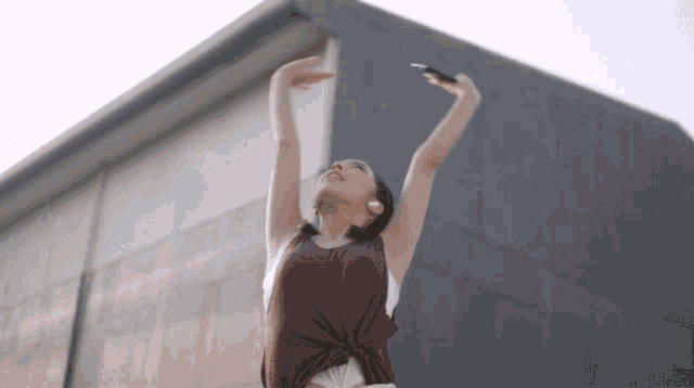 a woman in a maroon tank top holds her arms in the air