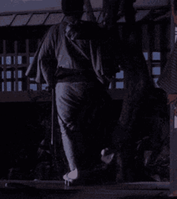 a man in a kimono holds a sword while sitting on the ground