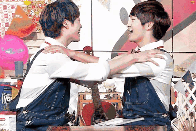 two young men are hugging each other in front of a guitar and a pink balloon
