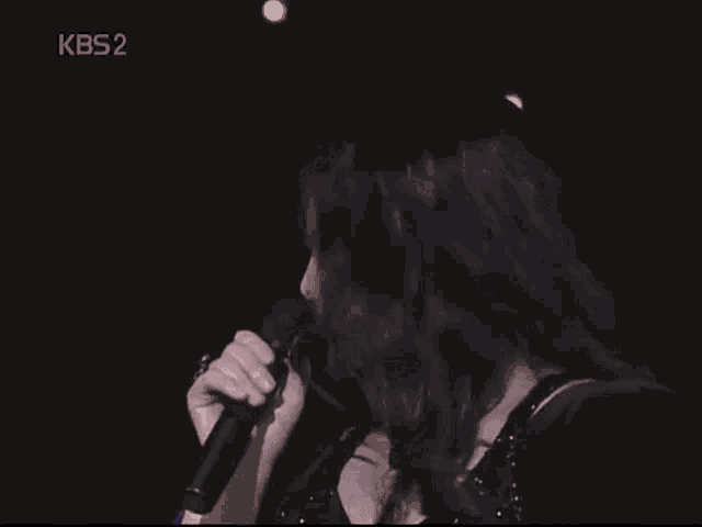 a woman singing into a microphone with kbs2 on the bottom left