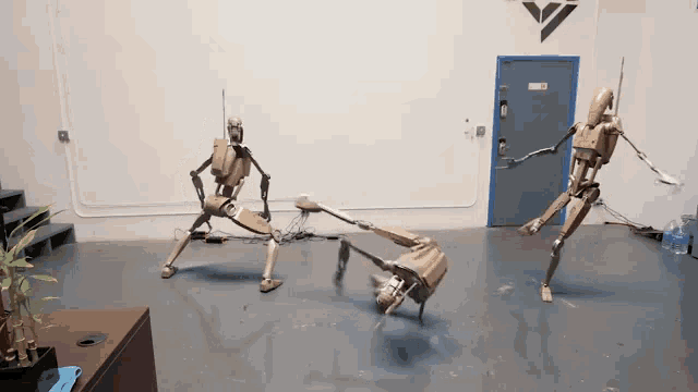 two cardboard robots are fighting in a room with a door that says exit on it
